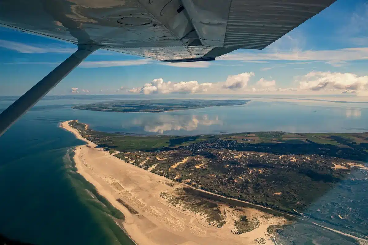Passenger looking out airplane window at European landscape and coastline below
