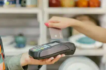 Hand holding a credit card above a digital payment interface showing reward points and currency conversion