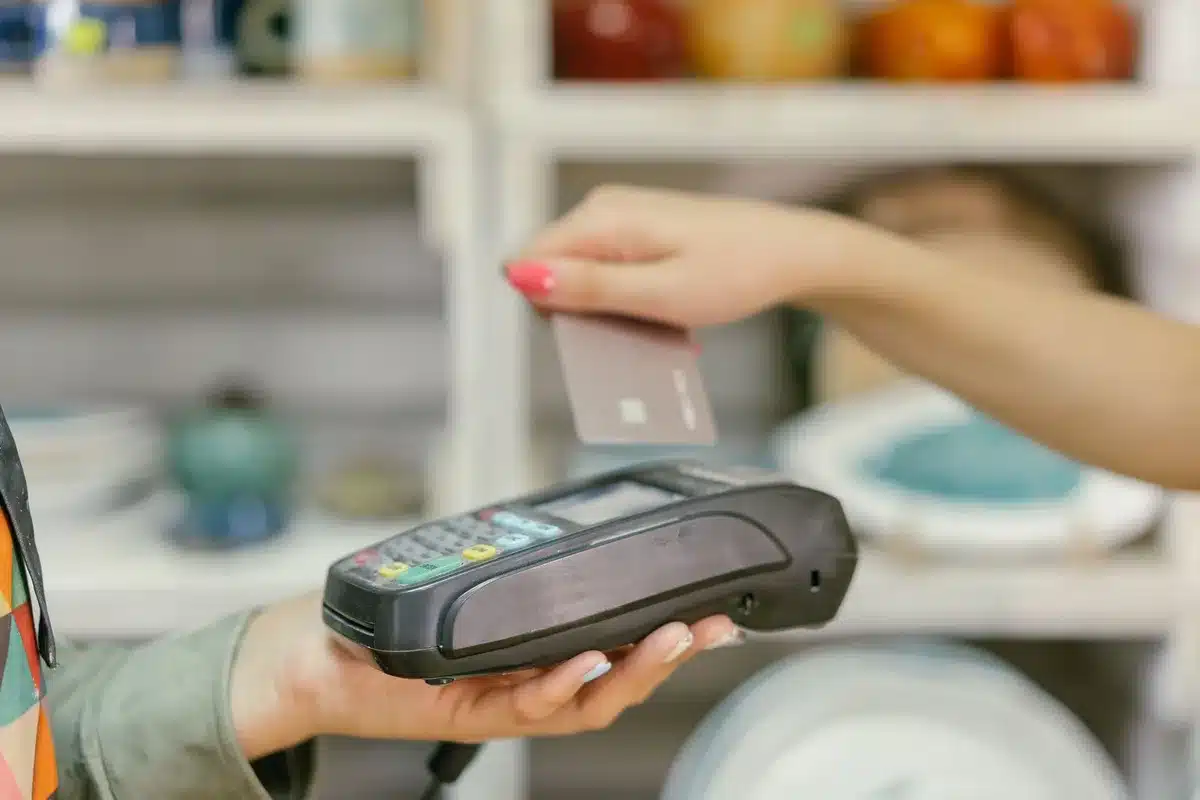 Hand holding a credit card above a digital payment interface showing reward points and currency conversion
