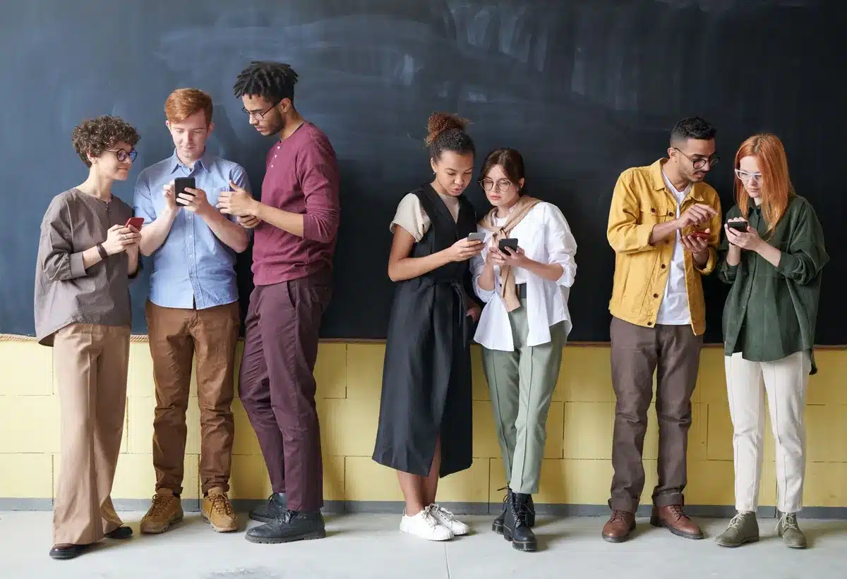 Multiple people checking smartphones with varied reactions to viral news