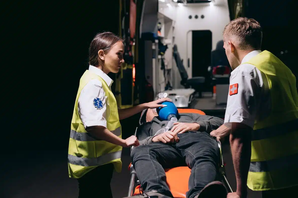 Emergency responders using oxygen mask and medical equipment on a patient.