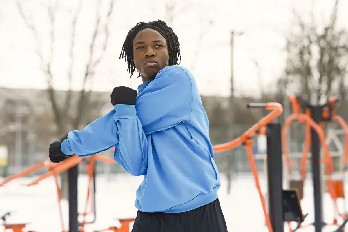 Athlete performing dynamic stretching and mobility exercises on a court at dawn.