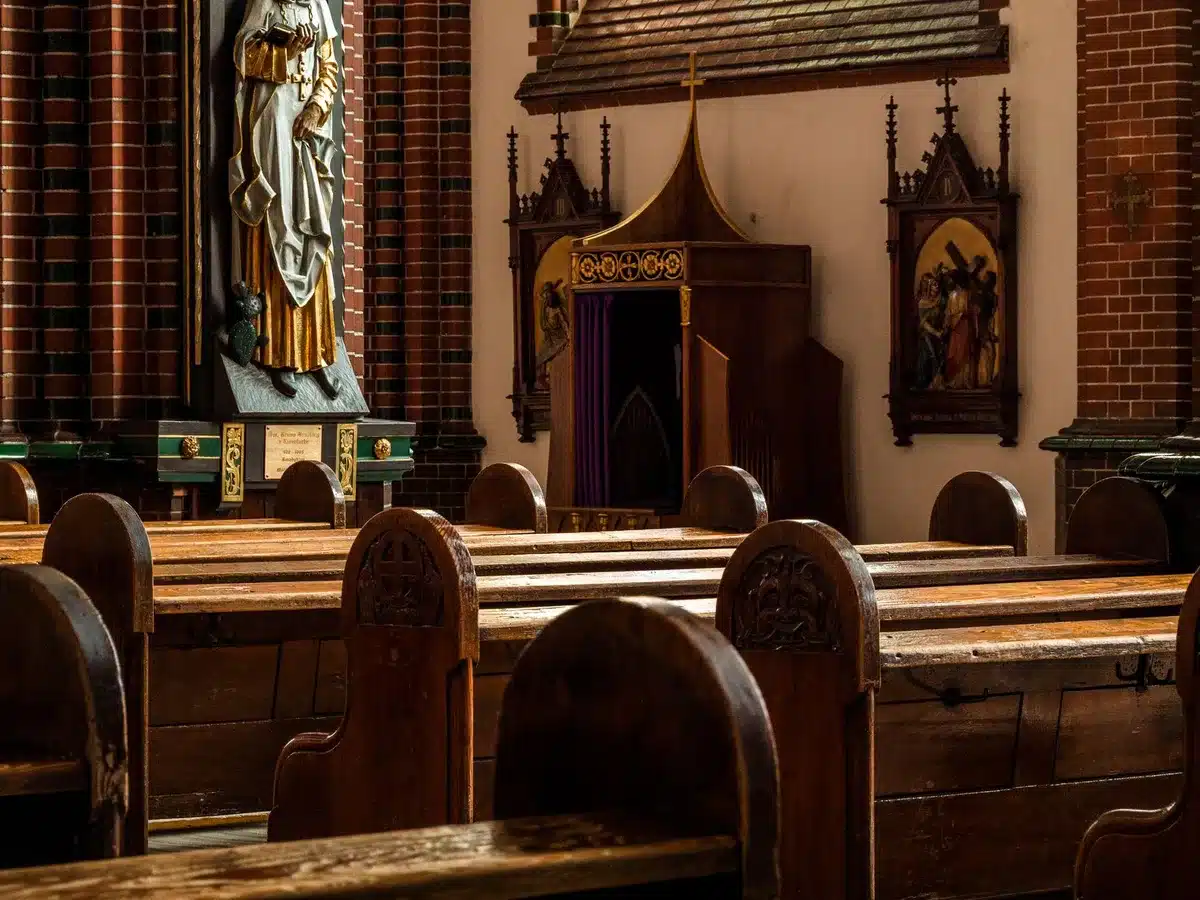 Hymnal on a wooden church pew with soft light streaming through stained glass windows