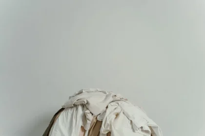 Hands gently folding soft white cotton fabric in warm light