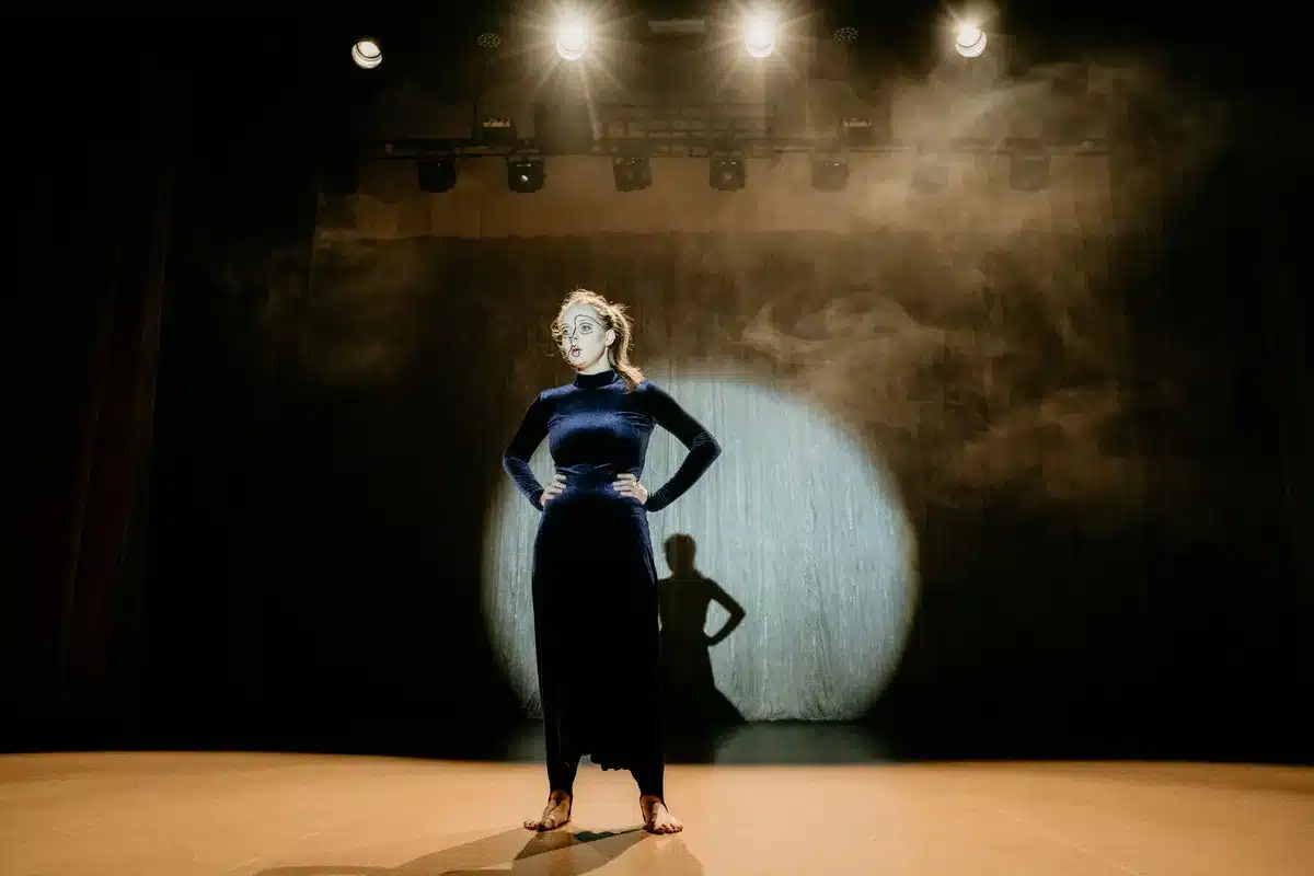 Three actresses performing under stage lights on a Broadway theatre stage
