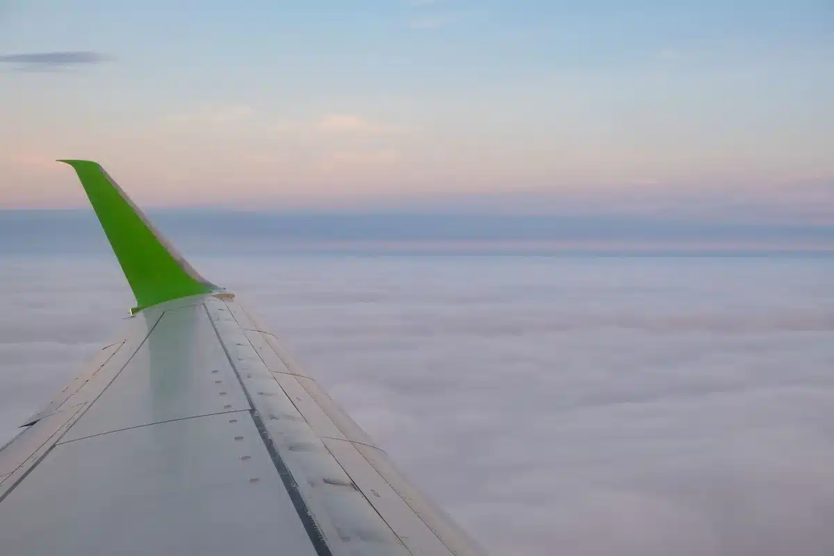 Blick aus dem Flugzeugfenster in große Höhe, zeigt die dünne Atmosphäre und klare Sicht über den Wolken