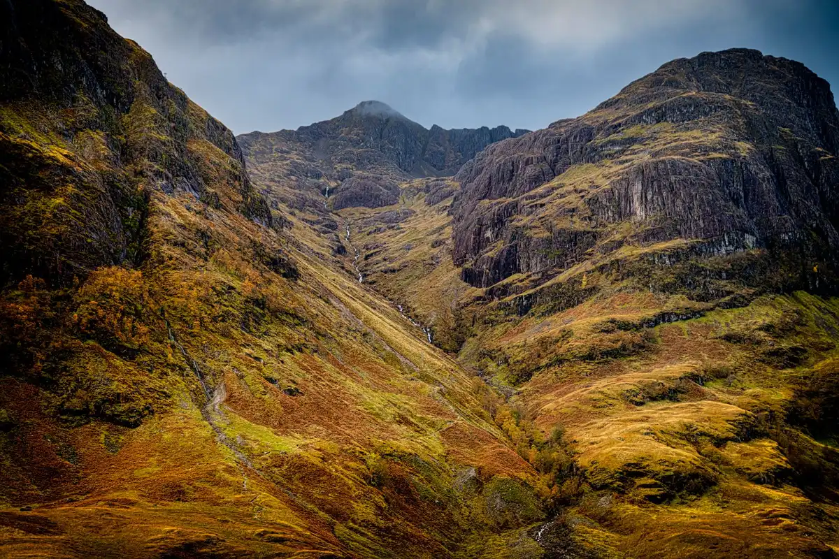 Vast Highland valley with golden birch trees and dramatic granite ridges in autumn light