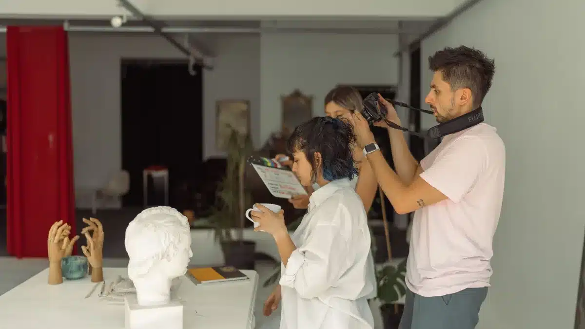 Emerging filmmakers and mentors collaborating in a creative workshop setting with cameras and production equipment.