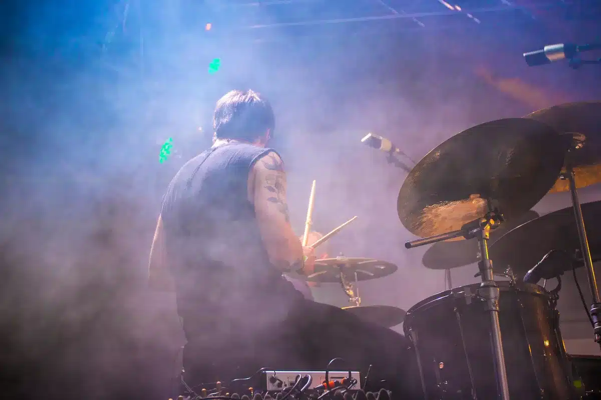 Drummer seated at drum kit performing onstage during a live concert