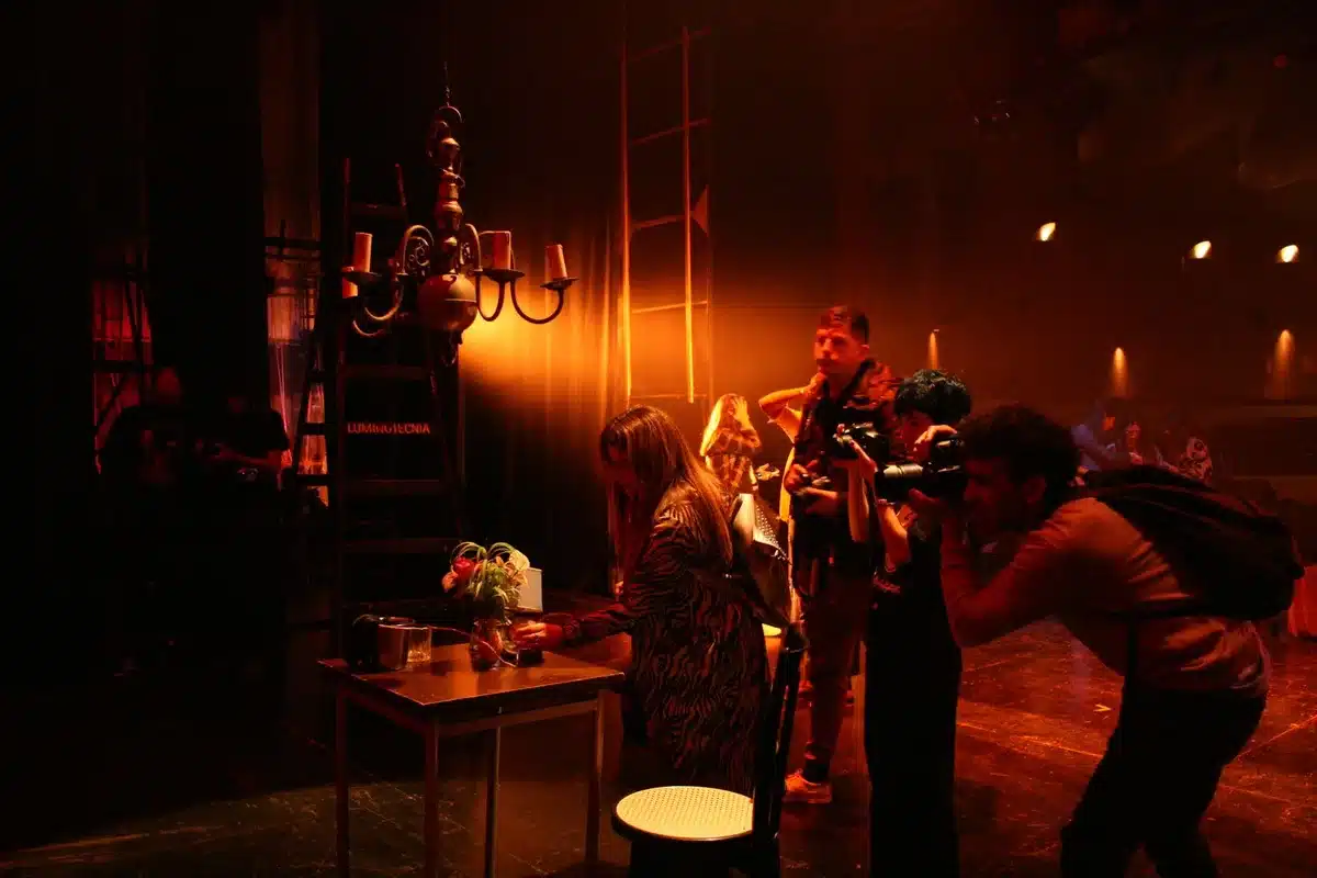 Traditional multi-camera sitcom set with theatrical lighting and live audience seating visible in background