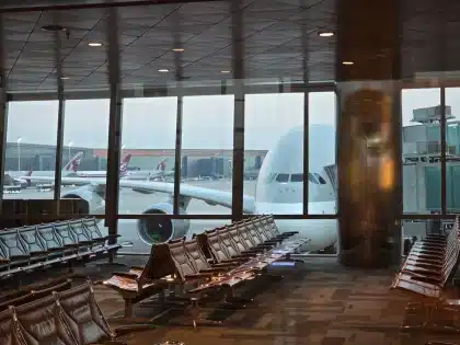 Passenger approaching an airport lounge entrance with boarding pass in hand