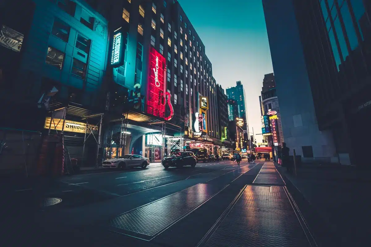 A couple walking hand-in-hand down a Manhattan street in soft evening light, viewed from behind.