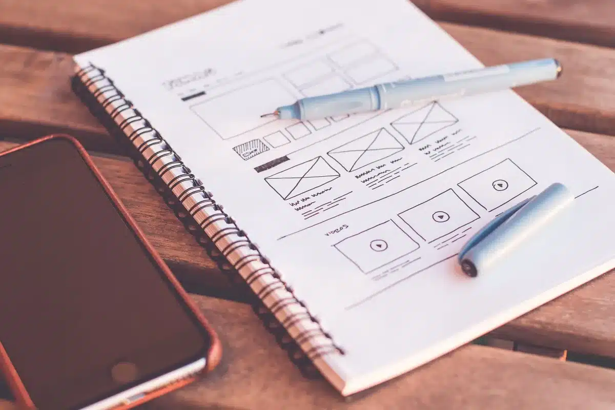 Designer's hand pointing at colored buttons on a digital interface mockup, showing UI design decisions.