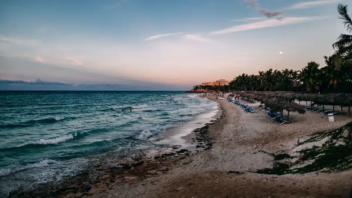 Serene Caribbean beach at sunset with calm turquoise waters and pristine sand.
