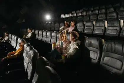 Audience members silhouetted in a cinema theater facing the illuminated screen