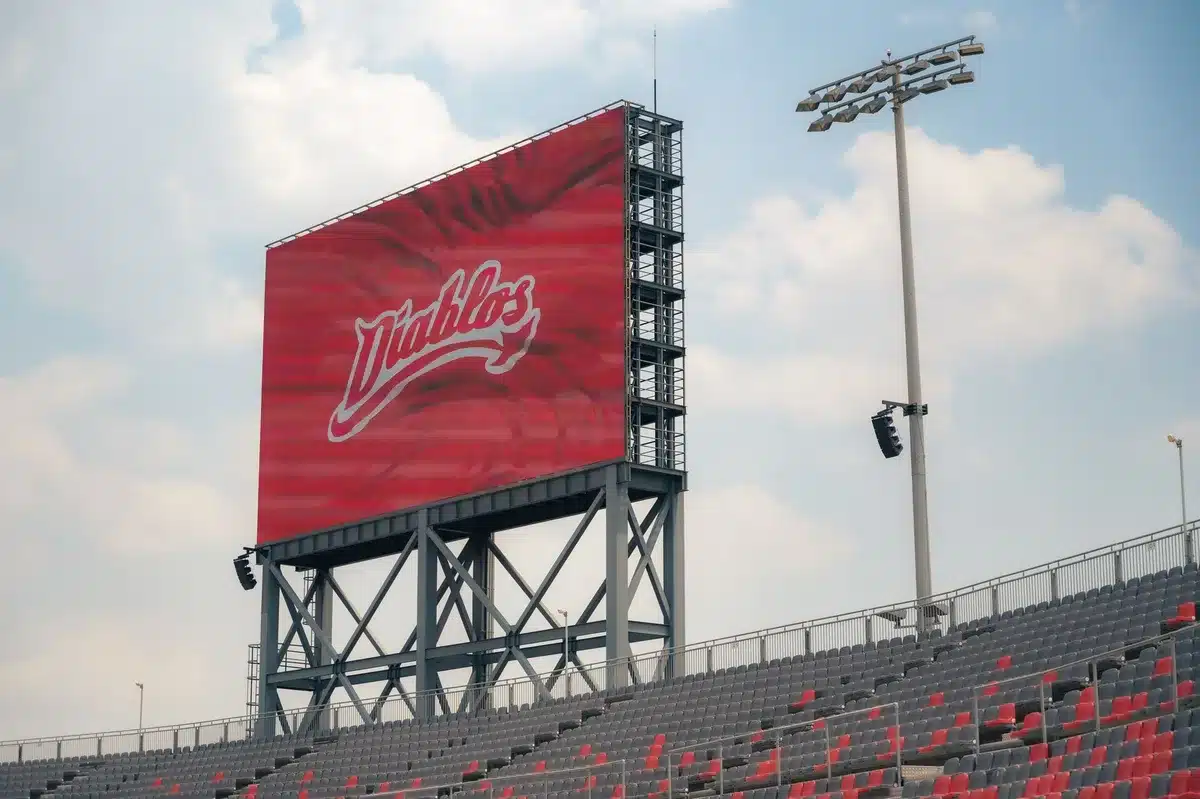 Large digital screens in a venue showing live sports content and gameplay statistics