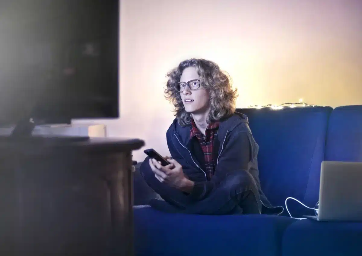 Silhouette watching a glowing TV screen with social media notifications streaming across the display