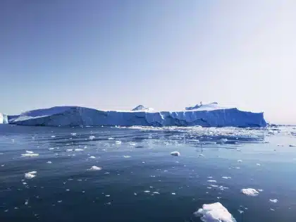 Aircraft flying over snow-covered Greenland landscape with glaciers and mountains
