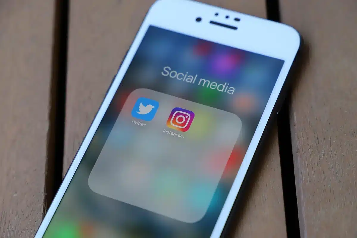 Person laughing while scrolling social media on a smartphone in low light