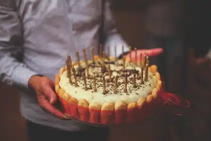Woman in casual clothes carrying a birthday cake in a supermarket aisle