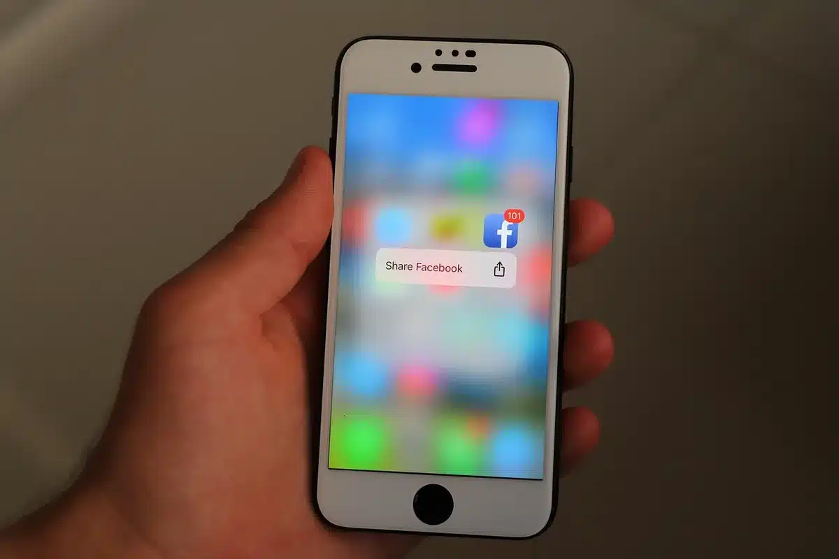 Person holding phone with social media notifications and icons on screen in dim lighting