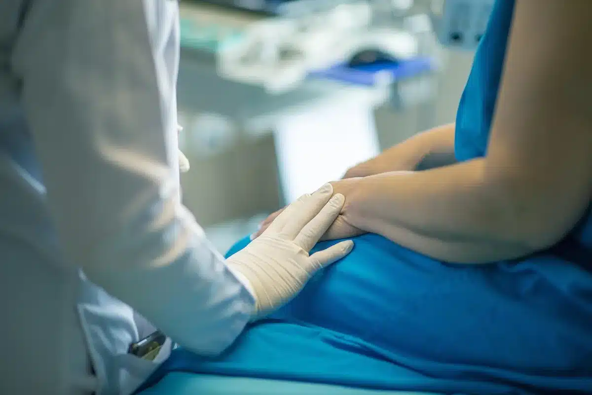 Anonymous patient in hospital bed with medical monitoring equipment and life support systems