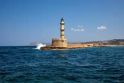 Chania waterfront with Venetian buildings, lighthouse silhouette and people strolling along the harbor