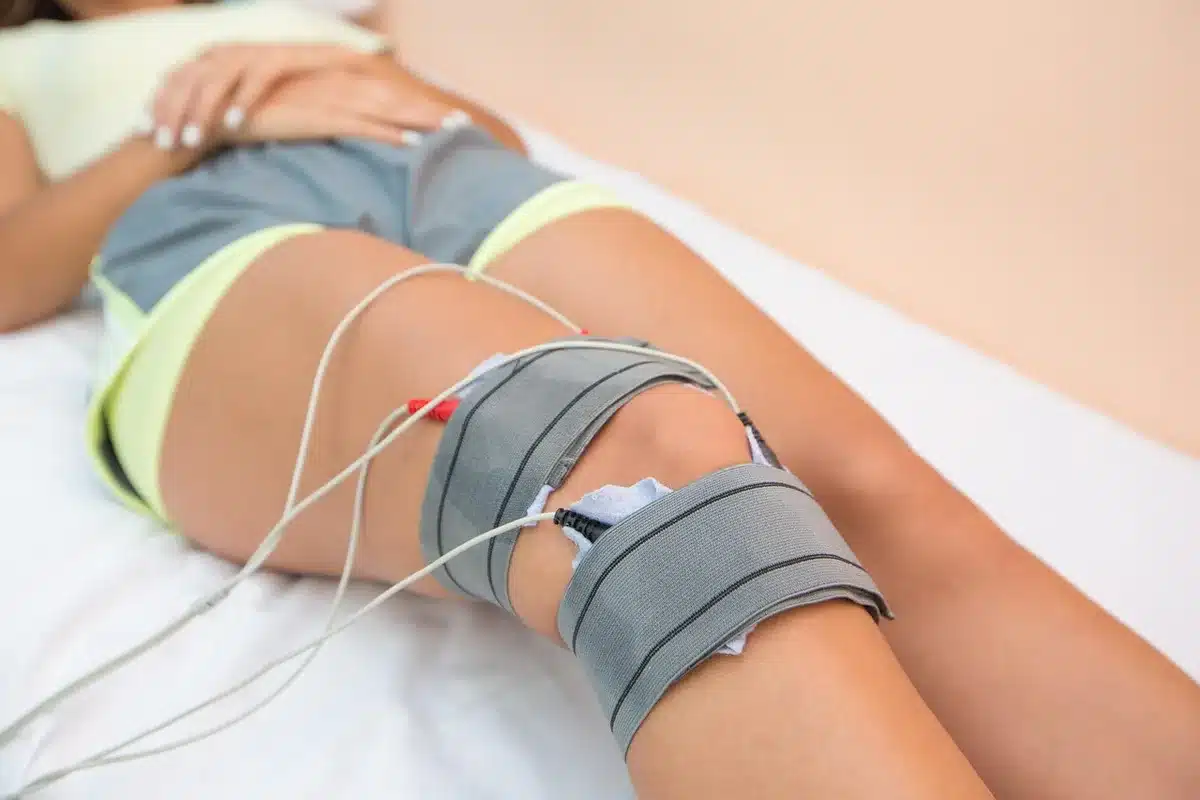 Hospital bedside with medical equipment and anonymous hands nearby
