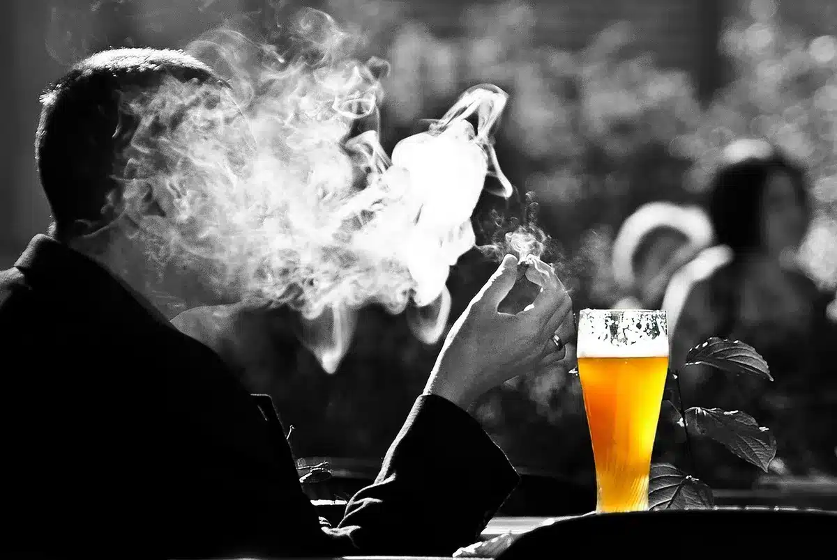 People enjoying drinks in a leafy beer garden under trees on a warm afternoon