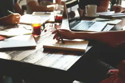Two professionals shaking hands at a business meeting with partnership documents on the table