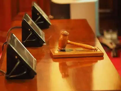 Silhouettes in a courtroom corridor with legal papers on a bench