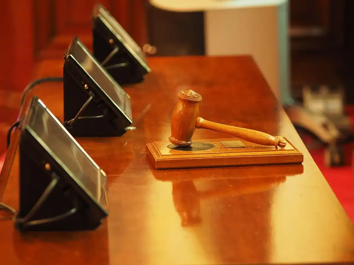 Silhouettes in a courtroom corridor with legal papers on a bench