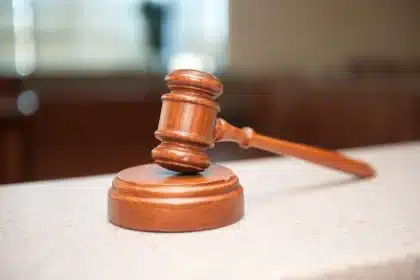 Wheelchair in a courtroom near a counsel table with legal folders and a judge's bench blurred