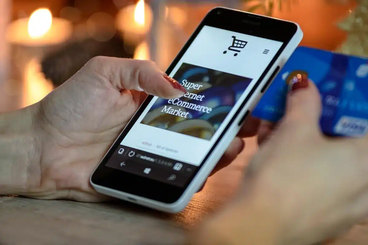 Hands holding a credit card while viewing an enrollment offer on a mobile device