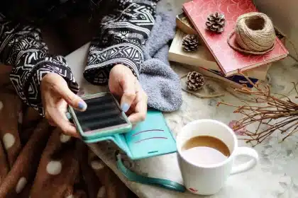 Hand holding smartphone displaying social media notifications and backlash symbols in red light