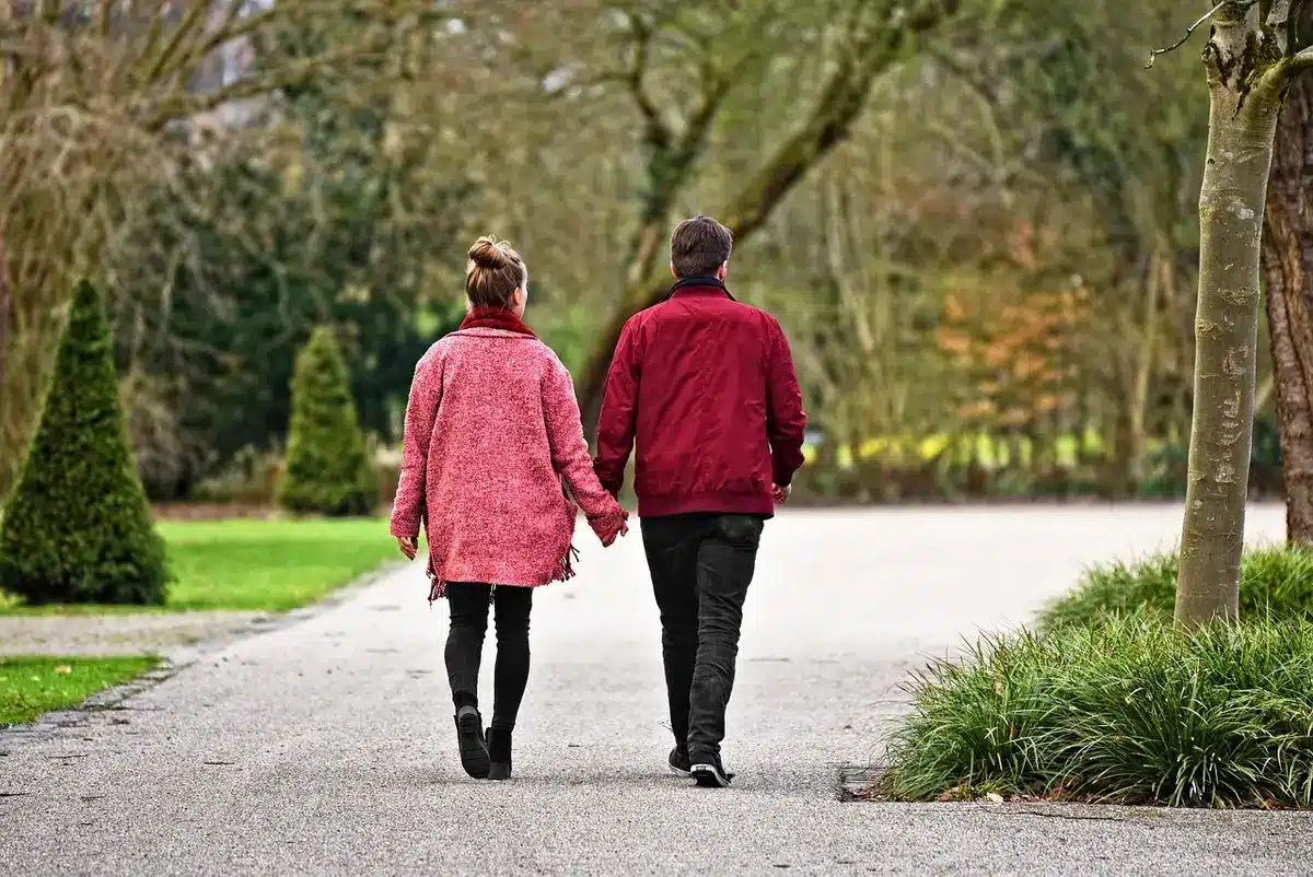 Anonymous couple walking with a covered stroller on a quiet street