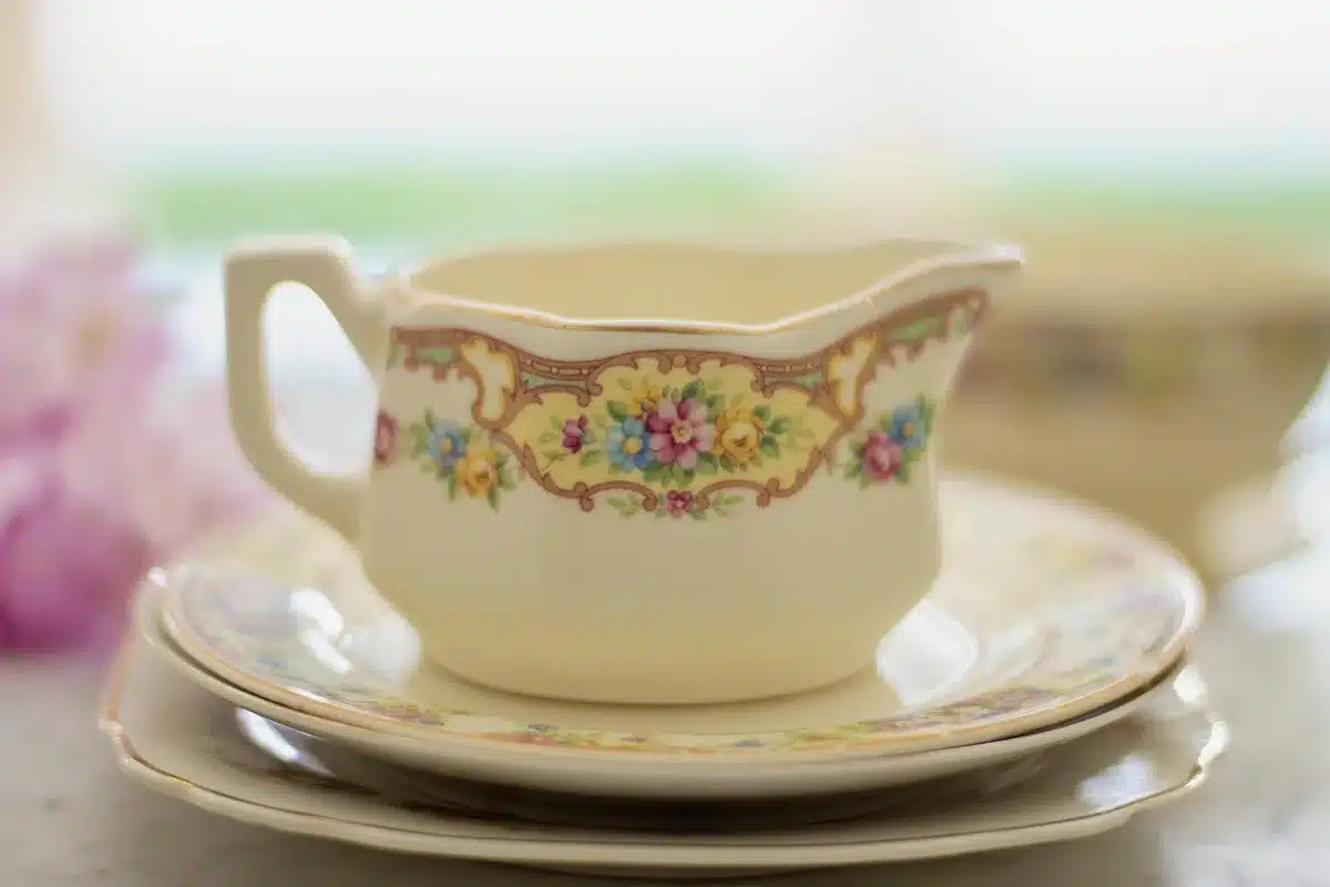 Deux silhouettes anonymes dans un salon ancien séparées par une table avec une tasse et un playbill