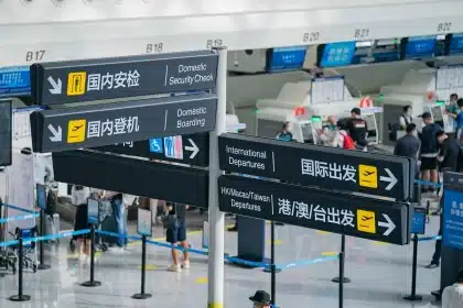 Silhouetted passengers at a gate with a delayed flight display and maintenance cart