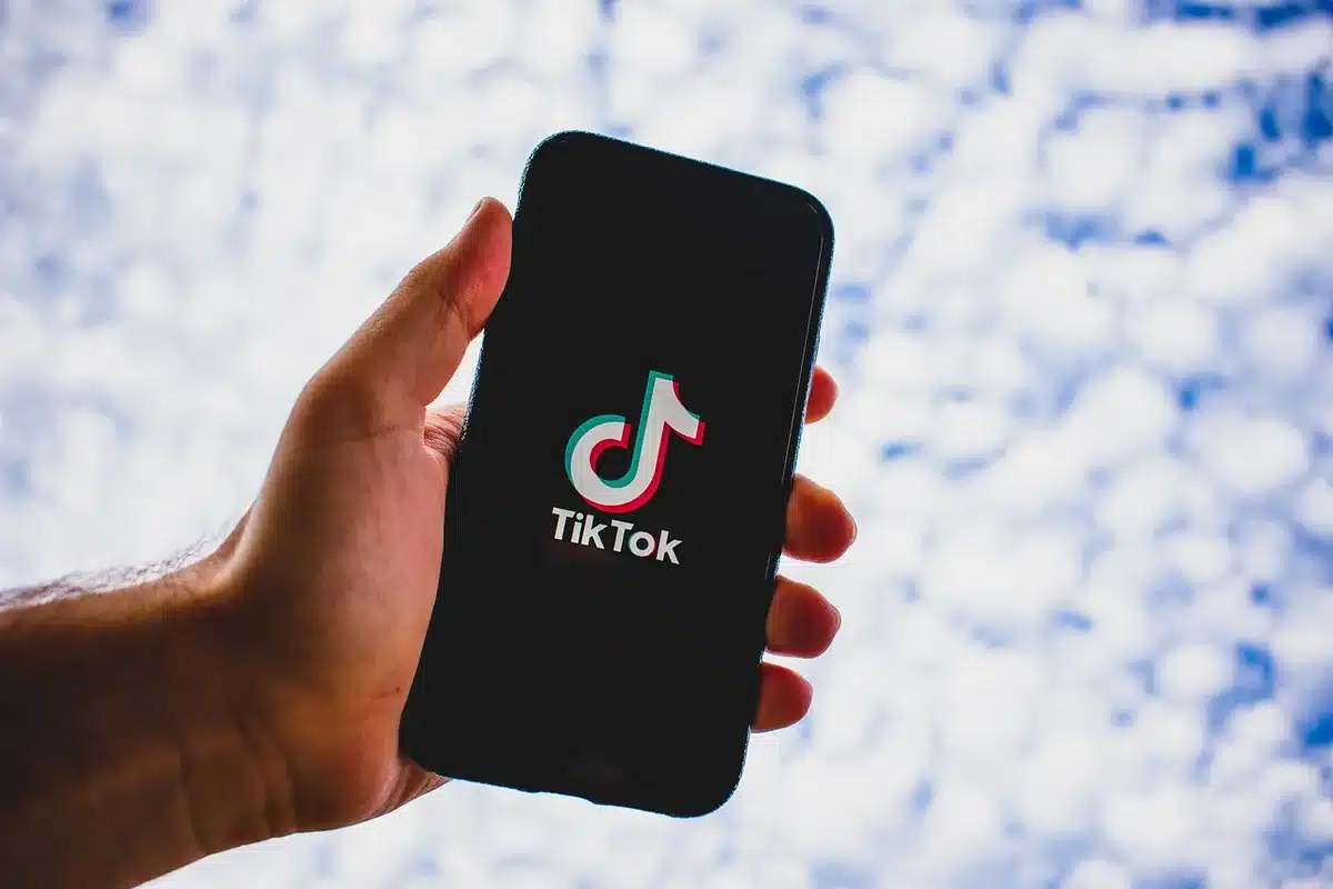 Mains anonymes tenant un smartphone affichant un fil social dans une salle de rédaction