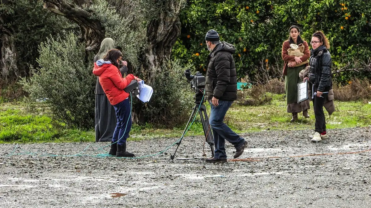 Filmmaking equipment on a production set with anonymous crew members working.