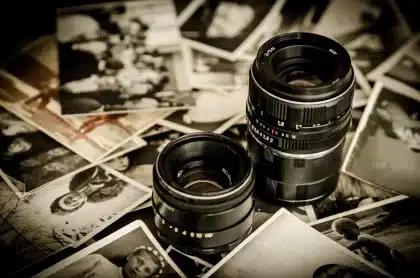 Hands holding a worn film script and vintage reels on a table in a sunlit office