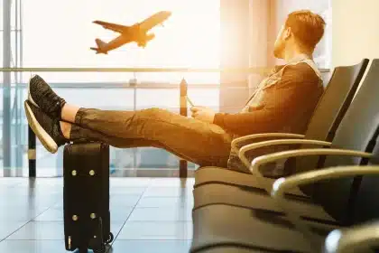 Passengers using laptops and tablets in an airplane cabin with sunlight through windows