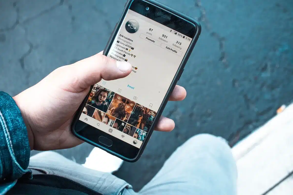 Hands holding a smartphone with social icons and business notebooks on a table