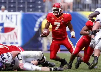 Silhouette of a college quarterback scrambling through linemen on turf