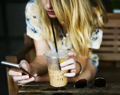 Hands arranging cosmetics, fabric swatches and a smartphone on a studio table