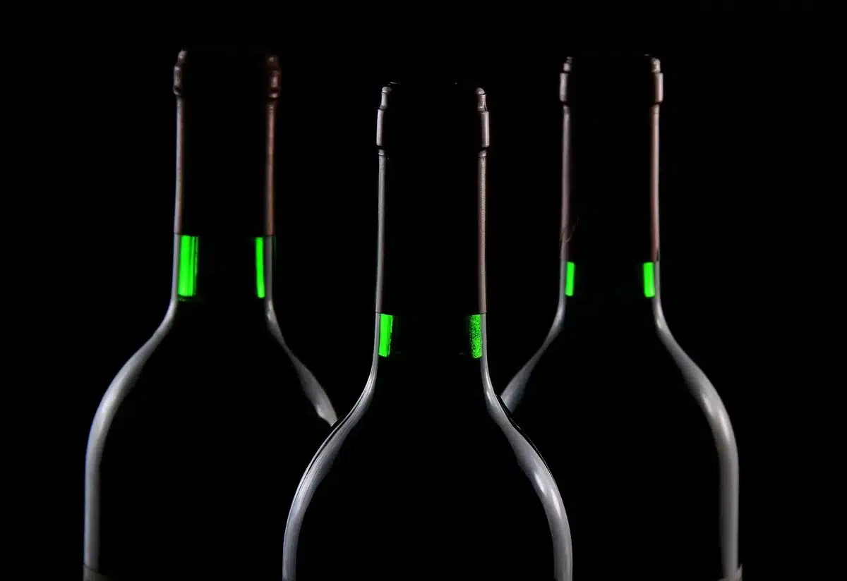 Hands packing padded wine bottles into a suitcase near an airport window