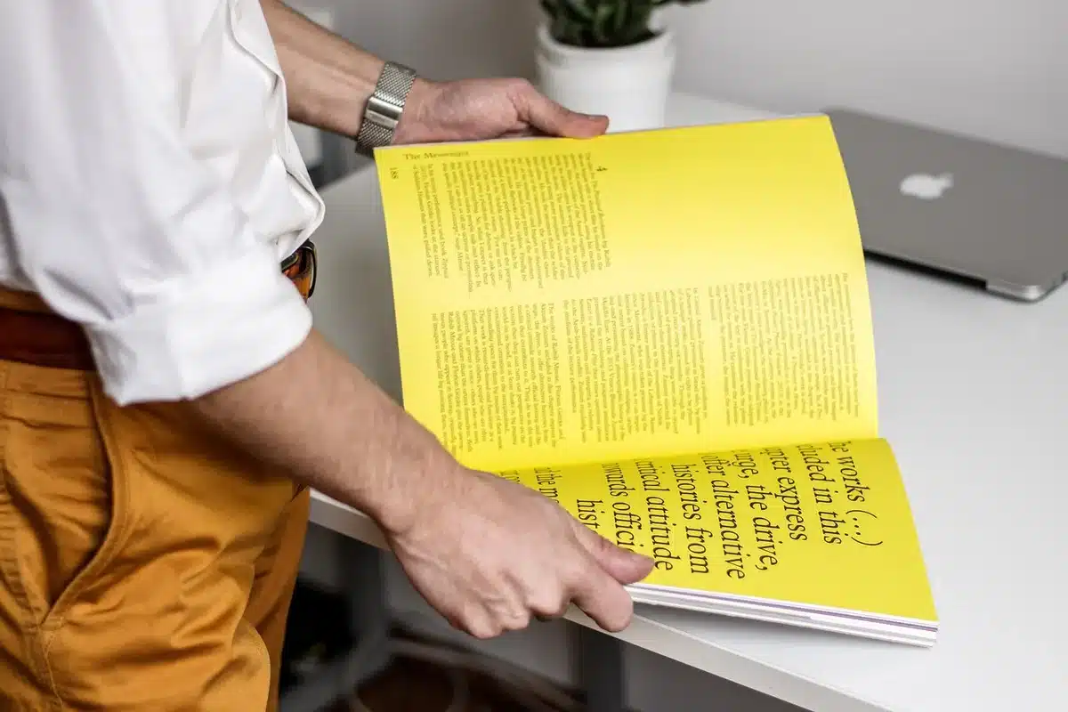 Person flipping through a magazine in sunlight, illustrating print cutting through digital noise