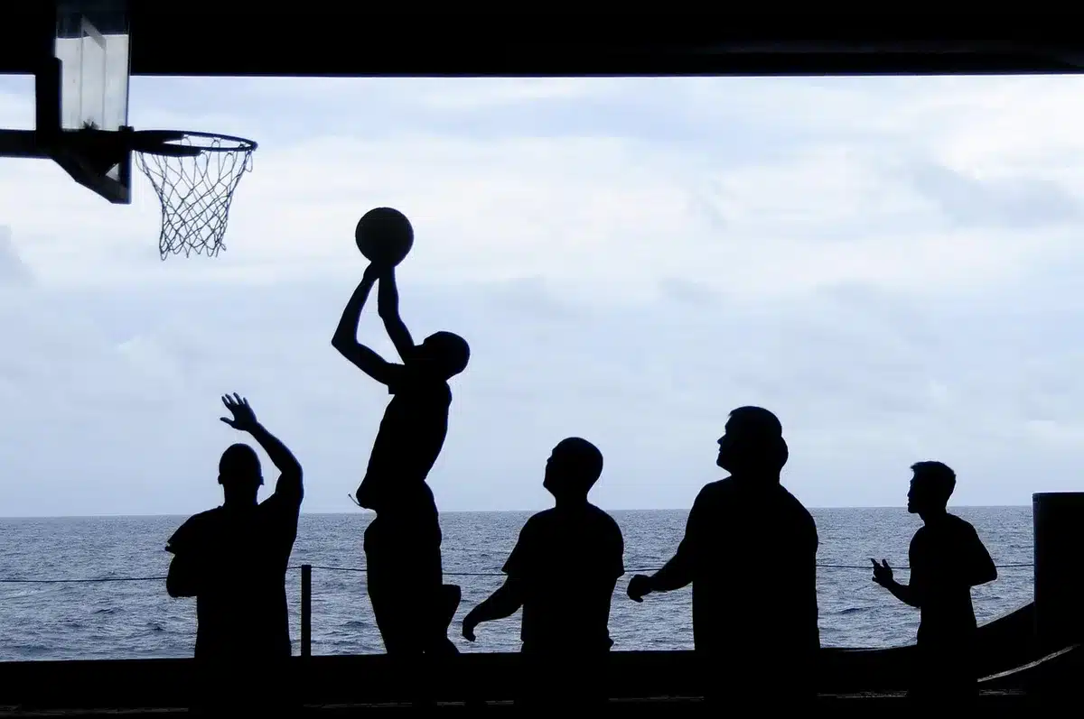 Wings and veterans sitting on a bench during an NBA training camp practice