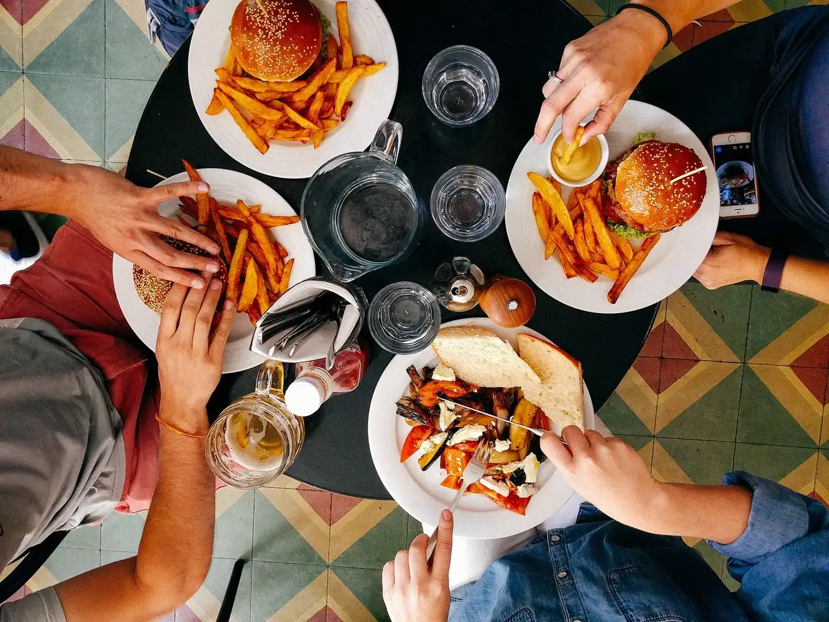 Hands passing a bill across a restaurant table with plates and a cocktail