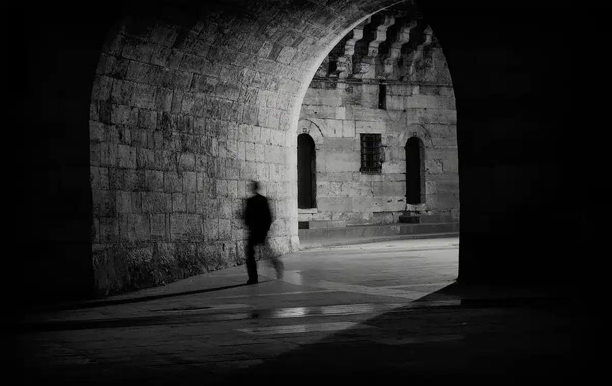 Silhouette of a person looking out a window, reflecting grief